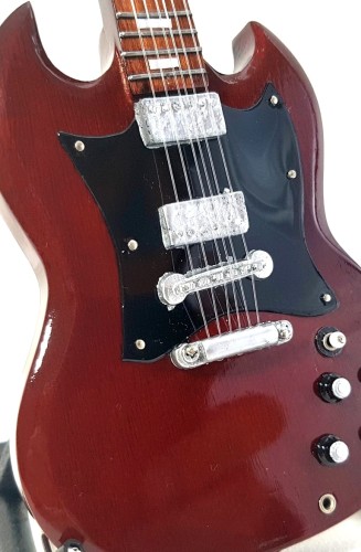 Ręcznie wykonana gitara z drewna mahoniowego ma około 27,5 cm wysokości i nawiązuje do scenicznego stylu Angus Younga.