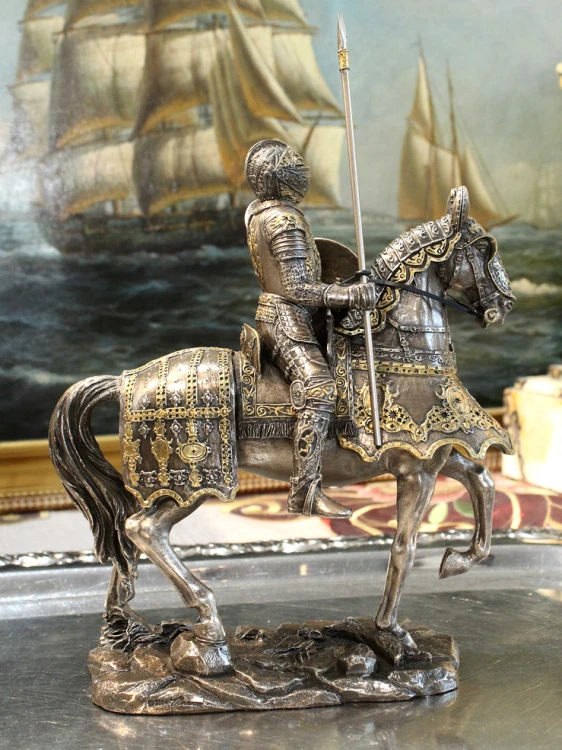 Figurka konnego rycerza z dekoracyjną zbroją i oporządzeniem konia, utrzymana w historycznym charakterze.