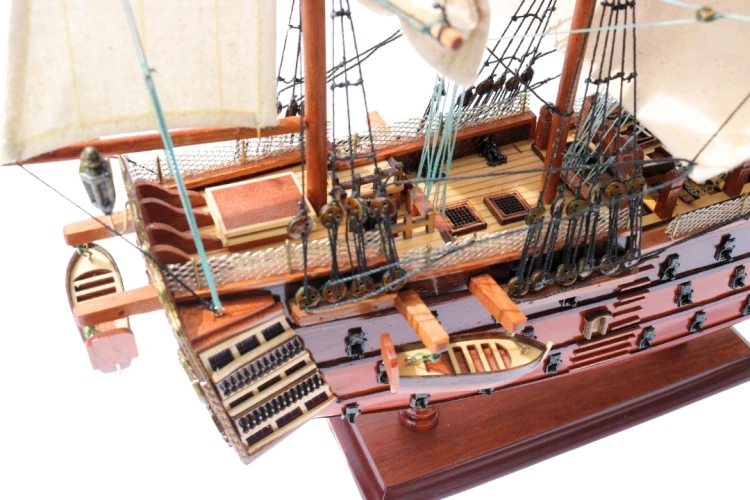 Model żaglowca HMS Victory z detalami pokładu, szalupą, takielunkiem i drewnianą podstawą ekspozycyjną