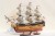 Model okrętu HMS Victory z licznymi działami, ozdobnym dziobem, żaglami i drewnianą podstawą ekspozycyjną