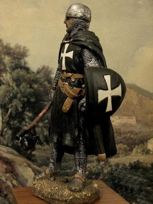 Rycerz zakonnik z tarczą i toporem i białymi krzyżami na tarczy i zbroi.